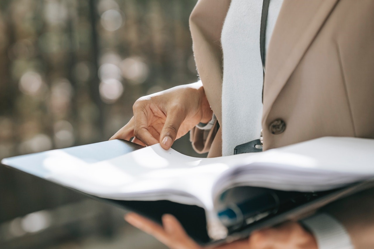 Woman’s hands holding a paper while flipping through a file with document